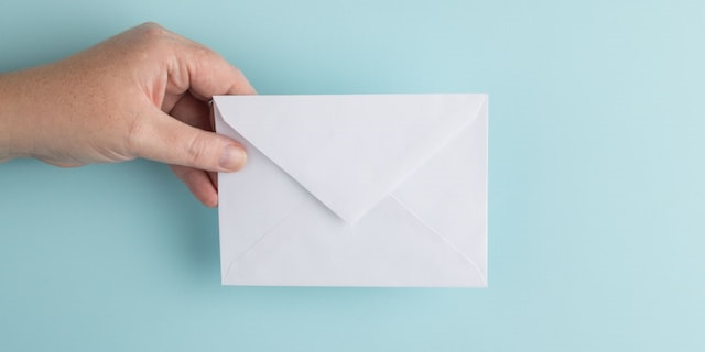 Bild: Eine Hand mit einem Briefumschlag ragt ins Bild.